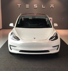 a white tesla car is on display in a showroom