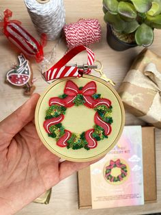 a hand holding a christmas ornament on top of a table next to other items