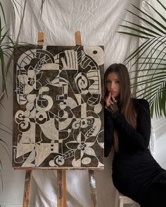 a woman sitting in front of an art piece