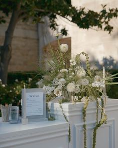 white flowers and greenery are on the mantle