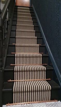 the stairs are lined with black and white striped carpet