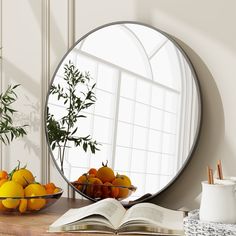 a mirror sitting on top of a wooden table next to a bowl of oranges