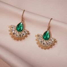 Make a statement with these stunning Art Deco Green Crystal Fan Dangle Earrings. The vibrant green crystals add a touch of elegance and glamour to any outfit. With their unique fan-shaped design, these earrings are a true statement piece. Handmade with attention to detail, they are made with high-quality materials to ensure durability and long-lasting beauty. Perfect for weddings, parties, or any special occasion, these earrings will make you feel like a true vintage diva. Add a touch of Art Dec Emerald Green Crystal, Beaded Party Dress, Vintage Inspired Jewelry, Razzle Dazzle, Fan Design, Crystal Dangle Earrings, Fan Earrings, Crystal Stones, Design Earrings