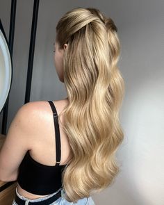 a woman with long blonde hair standing in front of a mirror