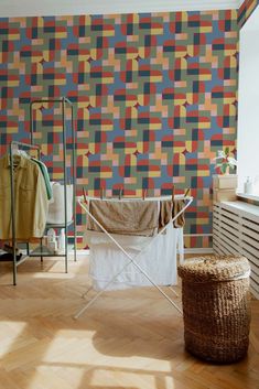 a laundry basket sitting on top of a wooden floor next to a wall covered in multicolored tiles