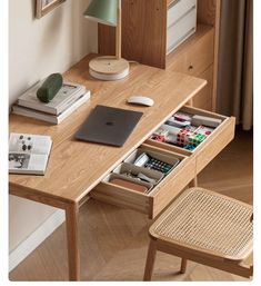 a wooden desk with an open drawer on it's left side and various items in the drawers