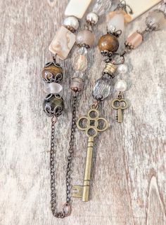 Stunning one-of-a-kind vintage and boho style assemblage necklace!! Lovingly handcrafted using the following materials: -Recycled vintage antique copper chain from a sun catcher  -Antique copper swirl spherical links and ornate toggle (that's in the front instead of the back, because it's way too pretty to hide) -Antique gold tone brass skeleton key charms  -Antique brass filigree bead caps  -Gunmetal tone brass filigree bead caps  -Upcycled lustrous ivory glass pearls from a vintage bracelet  - Rustic One-of-a-kind Festival Necklaces, Vintage Lariat Beaded Necklaces For Gifts, Vintage Lariat Beaded Necklaces As Gift, Vintage Lariat Beaded Necklace Gift, Vintage Lariat Beaded Necklace As A Gift, Bohemian Long Necklace With Vintage Charm, Artisan Necklaces With Vintage Charm, Artisan Vintage Charm Necklaces, Bronze Bohemian Necklace With Vintage Charm