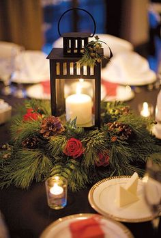 a candle is lit on top of a table decorated with evergreen and red roses, pineconi