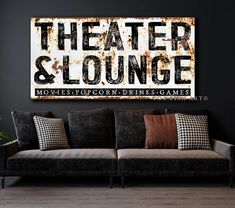 a couch sitting in front of a black wall with a sign on it that says theater and lounge