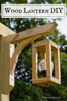 a bird feeder hanging from the side of a wooden structure with trees in the background