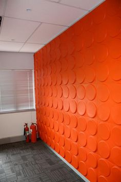 an orange wall with circles on it in the middle of a room next to a fire extinguisher