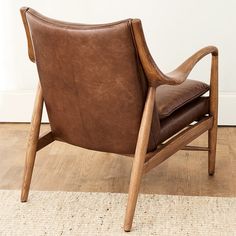 a brown leather chair sitting on top of a wooden floor next to a white wall