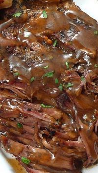 a white plate topped with roast beef covered in gravy and garnished with parsley