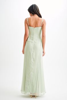 a woman in a long green dress looking back at the camera with her hand on her hip