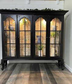 a black china cabinet with glass doors and wood floors