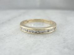 We've added a little bit of engraving along the top of this ring to provide texture and depth, a perfect contrast to the shining diamonds at the center! Crafted of yellow gold, this vintage ring has a slight dome, allowing it to look well against even a taller engagement ring.Diamonds: 15 diamonds = .22 carats, G in Color, SI in ClarityMetal: 14K Yellow GoldUS Size: 4 1/2, but can be sized to fit almost any finger (please see our sizing policies for more information). Marks: 51, O14K, Stamped on Timeless Gold Engraved Ring With Diamond Accents, Timeless Engraved Ring For Anniversary With Single Cut Diamonds, Engraved Round Cut Diamond Wedding Ring, Timeless Engraved Diamond Accents Ring For Anniversary, Classic Gold Engraved Ring With Diamond Accents, Timeless Engraved Anniversary Ring With Diamond Accents, Engraved Yellow Gold Wedding Diamond Ring, Engraved Yellow Gold Diamond Ring For Wedding, Engraved Yellow Gold Diamond Wedding Ring