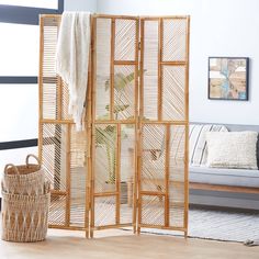 a room divider made out of bamboo with a plant in the corner and a basket on the floor