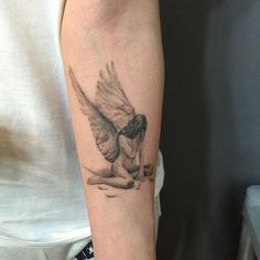 a person with a tattoo on their arm holding a bird in the air and touching it's body