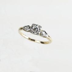 an engagement ring with three pear shaped diamonds on the side, set in yellow gold and white gold