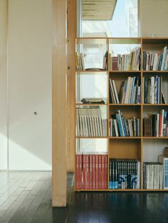 a bookshelf filled with lots of books next to a window in a room