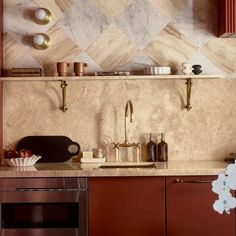 a kitchen with red cabinets and marble counter tops, gold faucets and brass accents