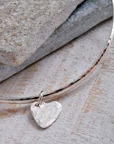 This sterling silver bangle is handmade in solid sterling silver.Handmade genuine sterling silver bangle with a D shape profile (the 'D' is on the outside edge of the bangle) with sterling silver heart charm.The bangle measures 2.3mm wide x 1.5mm thick with an inside diameter of 65mm.These beautiful bangles are genuine sterling silver with a hammered effect which really catches the light!They look great on their own or stacked up with other bangles!Bangle measures 65mm inside diameter as a stand Silver Star Bracelet, Beautiful Bangles, Thumb Rings Silver, Hammered Bangles, Sterling Silver Bangle, Sterling Silver Rings Bands, Hammered Sterling Silver, Stacked Bangles, Star Bracelet