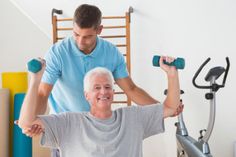 an older man is exercising on a stationary exercise bike while his trainer looks at him