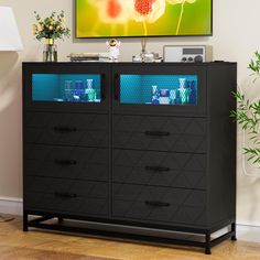 a television is mounted on the wall above a black dresser with glass doors and drawers