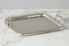 a silver tray with handles on a marble surface