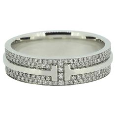 Here we have a a fabulously crafted diamond band ring from the world renowned jewellery designer Tiffany & Co. This ring forms part of their T True collection and is the wider model featuring the iconic T motif around the entire band with two rows of pavé set diamonds for company. Condition: Used (Excellent) - Professionally polished to appear brand new Weight: 8.0 grams Ring Size: S (60) Band Width: 5.8mm Total Diamond Weight: Approx. 0.56ct Diamond Details: Approx. Colour: F-G, Clarity: VS Band Width: 3.5mm Marked: ‘Tiffany & Co.’ ‘Au750’ 'ITALY' RRP: £9,950 Box: Tiffany & Co. Box Tiffany Diamond Band Ring, Tiffany Wide Band Ring, Wide Diamond Rings, Tiffany Diamond Ring, Tiffany Diamond, Tiffany T, Contemporary Engagement Rings, Diamond Band Ring, Pave Diamond Ring