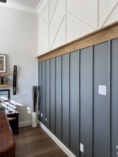 a room with wood floors and gray paneling on the walls, along with a wooden desk