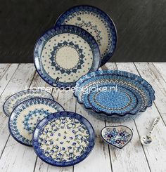 four blue and white plates sitting next to each other on a wooden table with spoons