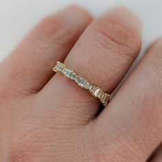 a woman's hand with a yellow gold band and diamond ring on her finger