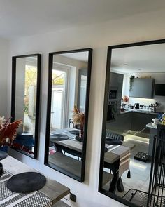 three mirrors are hanging on the wall above a dining room table