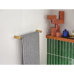 a towel rack is next to a green tiled wall with a wooden cross on it