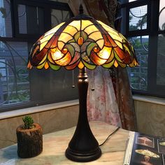 a lamp that is on top of a table next to a book and potted plant