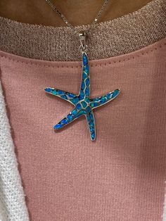 Embark on a Florida Keys tropical adventure with this eye-catching pendant necklace. Starfish have quite a few meanings and connotations attached to them but many times they represent renewal and regeneration. Starfish are also well known to represent infinite and divine love. According to legend, starfish are reflections of stars in the sky that inhibit the ocean floor symbolizing rebirth and longevity. This piece is crafted in real 925 sterling silver and inlaid with iridescent blue opal gemst Blue Star Charm Pendant Necklace, Blue Pendant Necklace With Star Charm, Blue Starfish Charm Necklace, Ocean-inspired Blue Jewelry With Star Charm, Unique Starfish Jewelry As A Gift, Blue Necklaces With Starfish Charm For Gifts, Blue Star-shaped Nickel-free Necklace, Blue Sterling Silver Necklace With Starfish Charm, Blue Sterling Silver Necklaces With Starfish Charm