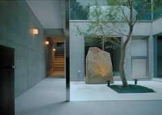 a large rock sitting in the middle of a room next to a tree and stairs