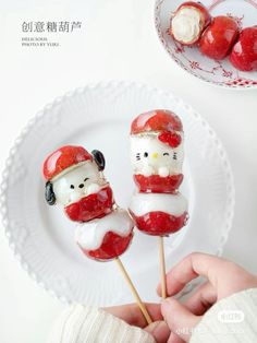 a person is holding two marshmallows with santa hats on them and they are sitting on a plate