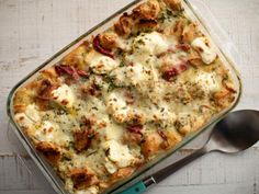 a casserole dish with meat and cheese in it on a wooden table next to a spoon