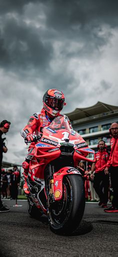 a man riding on the back of a red motorcycle down a street next to other people