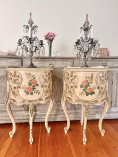 two antique side tables with flowers painted on them and glass vases in the background