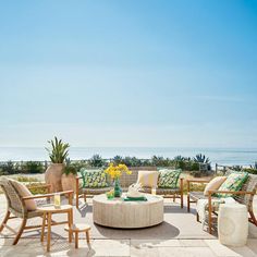 an outdoor seating area with chairs and tables on the patio next to the ocean is shown