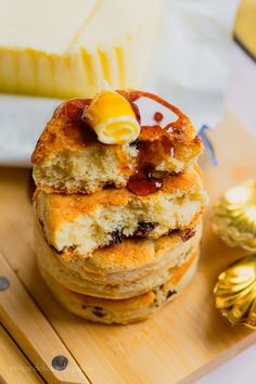 a stack of pancakes sitting on top of a wooden cutting board next to butter and jelly