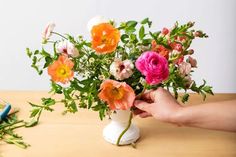 a person is arranging flowers in a vase on a table next to a pair of scissors