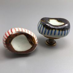 two small ceramic knobs with striped designs on them, one is open and the other has a hole in it