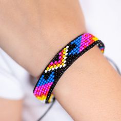 Get ready to make a statement with the Bold Bracelet! This vibrant, handwoven accessory features eye-catching, indigenous patterns in a riot of bright colors. It’s designed to stand out and add a pop of fun to any outfit. With an adjustable sliding knot on the back, it ensures the perfect fit for any wrist. Whether you’re dressing up for a festival or just want to spice up your everyday look, the Bold Bracelet is here to bring a splash of joy and culture to your style. Slip it on and let your bo Adjustable Rainbow Bracelets For Festivals, Multicolor Beaded Friendship Bracelets, Adjustable Multicolor Beaded Friendship Bracelets, Adjustable Rainbow Braided Beaded Bracelet, Resizable Beaded Bracelets For Festivals, Trendy Resizable Beaded Bracelets For Festivals, Adjustable Beaded Rainbow Friendship Bracelets, Adjustable Rainbow Beaded Friendship Bracelets, Adjustable Colorful Bohemian Beaded Bracelets