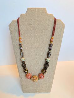 Stunning Handmade Dayak (Borneo) Beads Necklace. Hand painted beads with different color tone.  The unique and meticulous patterns inscribe on each bead. Hailing all the way from the island of Kalimantan in Indonesia, these beads are carefully handcrafted using the finest materials including carnelian, crystal, clay and other natural stone.  In the same way each stroke of red, yellow and blue paint depicts the unequivocal talents of the craftsman. Orange Bohemian Hand-strung Beaded Necklace, Traditional Double Strand Beads For Gift, Bohemian Czech Glass Beads With Large Beads, Bohemian Czech Glass Large Beads, Multicolor Wooden Beads Oval Necklaces, Multicolor Wooden Oval Beads Necklace, Multicolor Hand-strung Round Beads Necklace, Multicolor Hand-strung Round Bead Necklaces, Bohemian Czech Glass Round Bead Necklaces