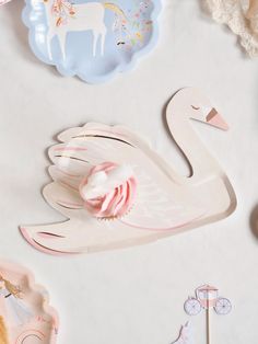 a swan shaped cupcake holder next to some other paper plates and decorations on a white surface