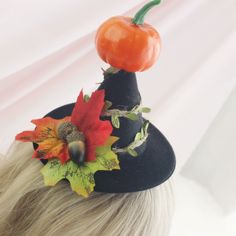 a woman with blonde hair wearing a black hat and flower decoration on top of her head